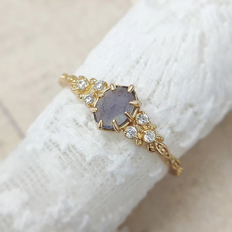925 ring with a central purple stone and diamond accents on a white fabric background