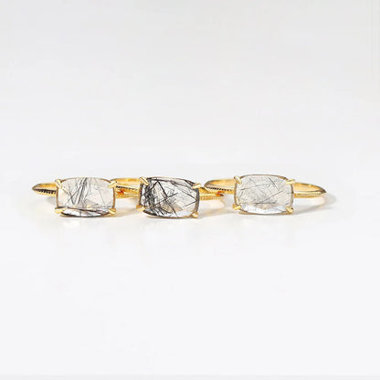 Gold rings with three clear gemstones on a white background