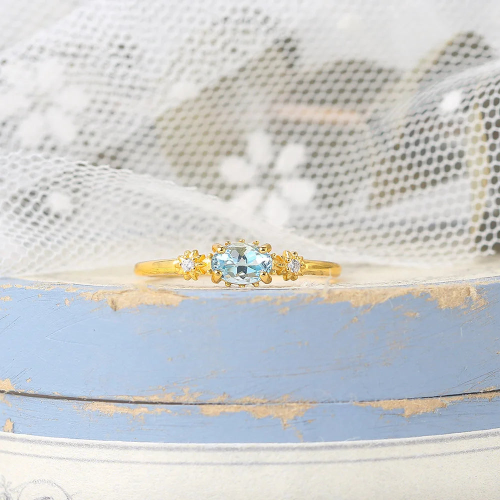 Gold ring with a blue topaz gemstone on a textured surface