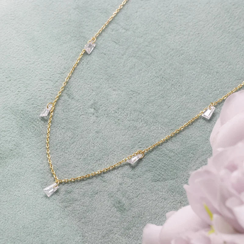 18kt Gold platd necklace with clear gemstones on a light green background