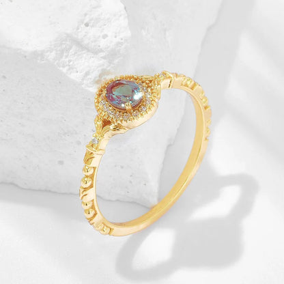Gold ring with a colorful gemstone on a textured white background