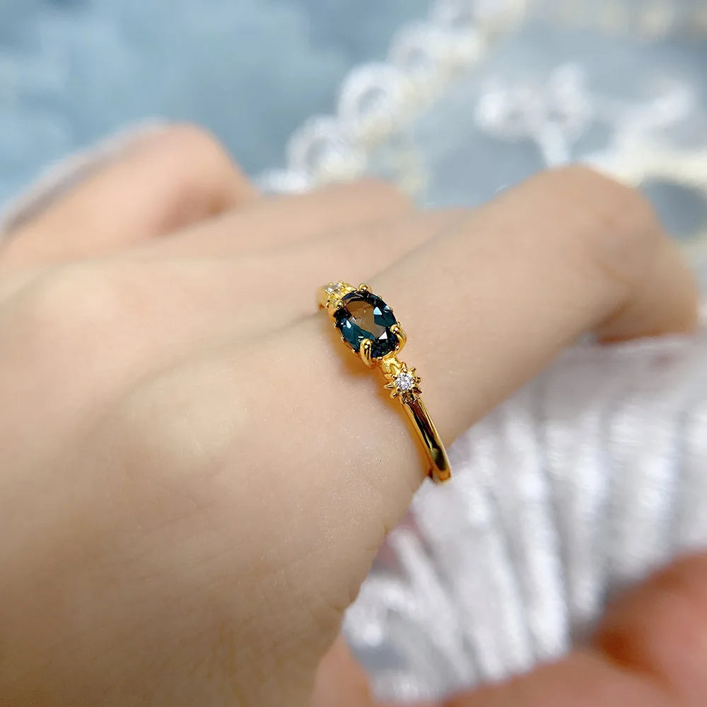 Gold ring with a gemstone on a person's finger against a blurred background