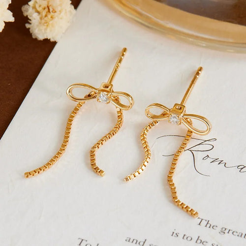 Gold bow earrings with moissanite accents and tassel chains