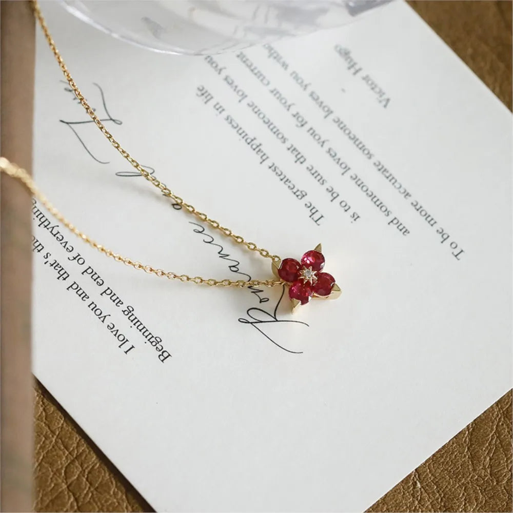 Ruby clover pendant necklace displayed on an open book